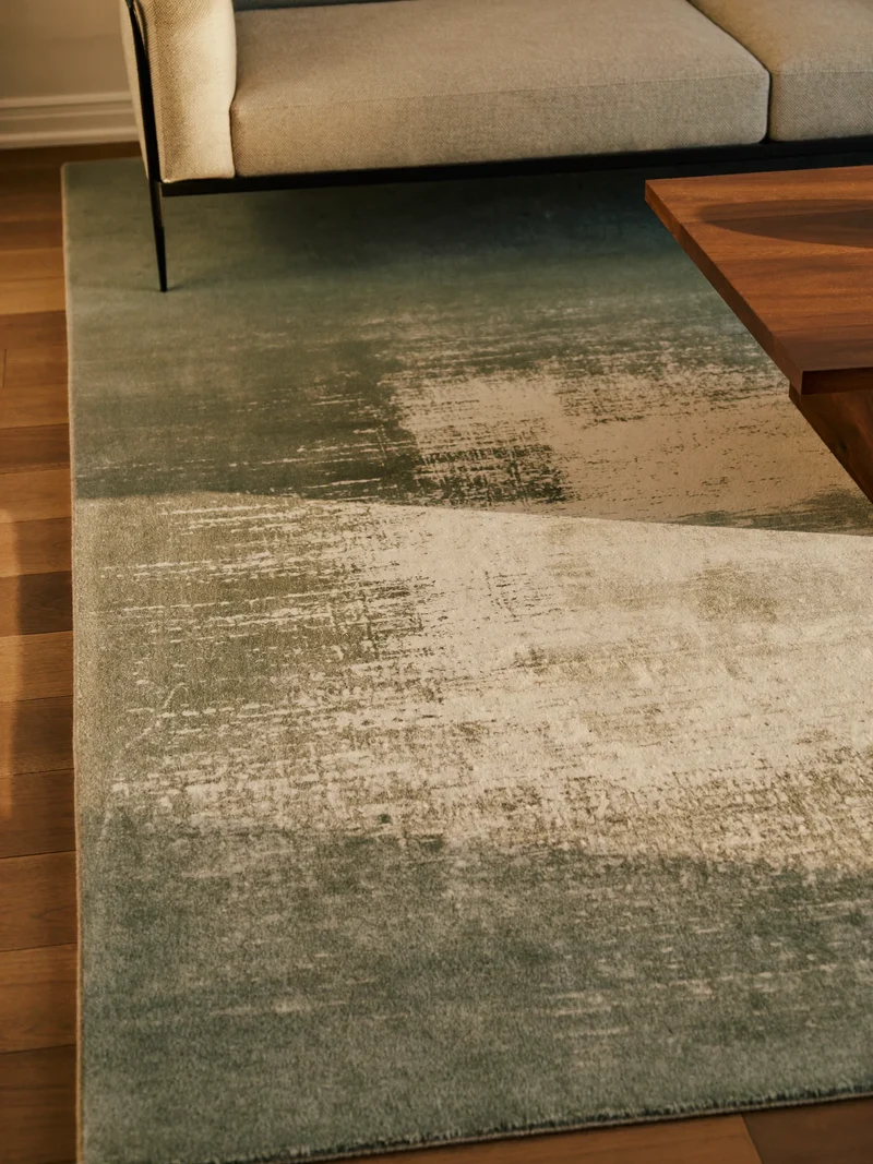 Tapis abstrait gris et sauge sous un canapé moderne et une table basse